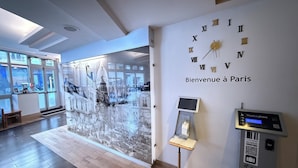 A hotel lobby with a large wall clock, a reception desk, and a digital kiosk. - Holiday Inn Paris - Montmartre by IHG (Paris)