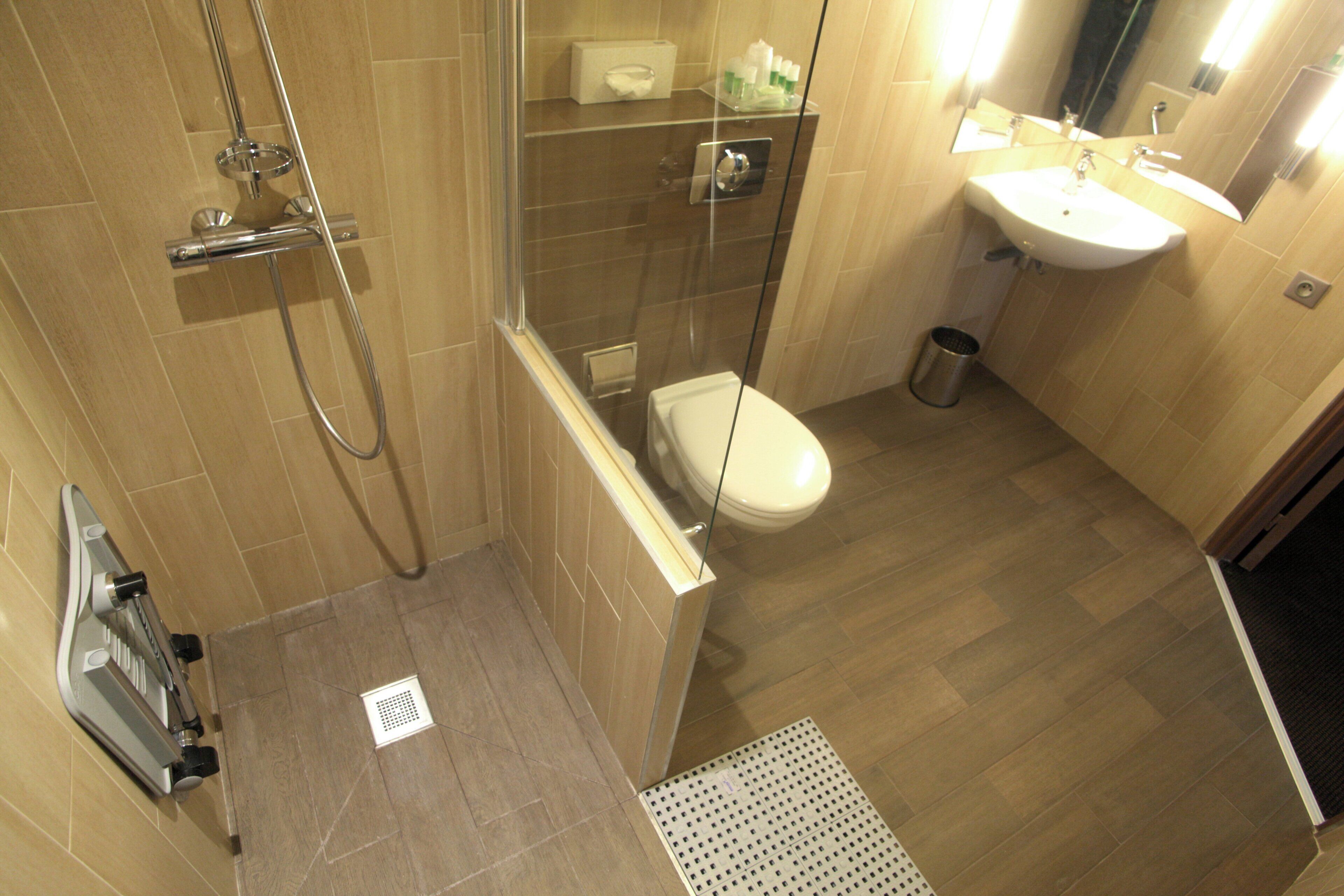 A modern bathroom with a glass shower enclosure, a toilet, and a sink.