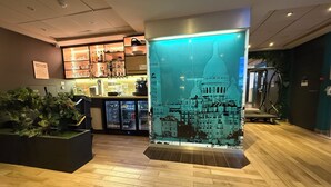 A hotel lobby with a large decorative wall, a reception desk, and a seating area with a plant. - Holiday Inn Paris - Montmartre by IHG (Paris)