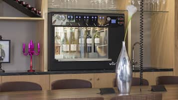 A bar area with a wine dispenser, a vase with a flower, and a phone on the counter.