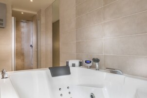 A modern bathroom with a large bathtub, a shower area, and a digital control panel.