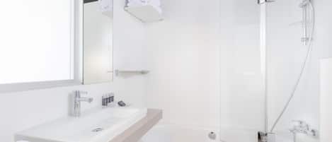 A modern bathroom with a glass-enclosed shower, a white sink, and a towel rack.