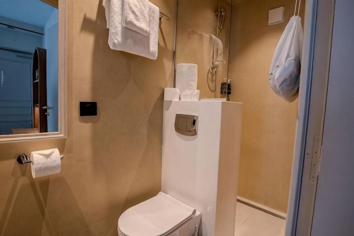 Un baño con inodoro, ducha y toallero.