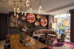 A modern hotel lobby with a wooden reception desk, a sofa, and a circular wall display.