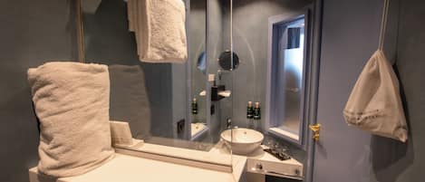 A bathroom with a white sink, a mirror, and two towels hanging on hooks.