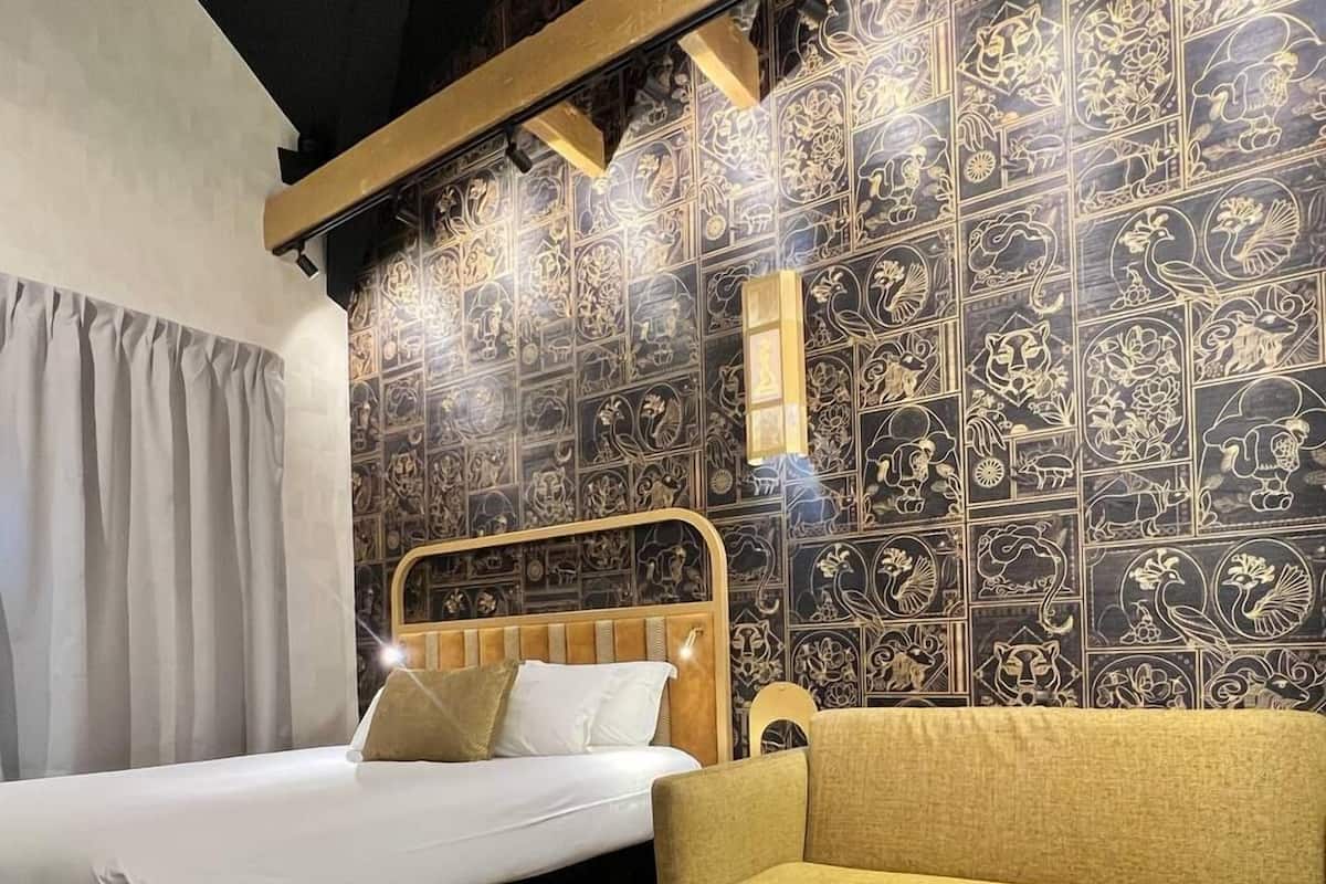 Una habitación de hotel con una cama, un sofá, una mesa redonda y una pared con estampado.