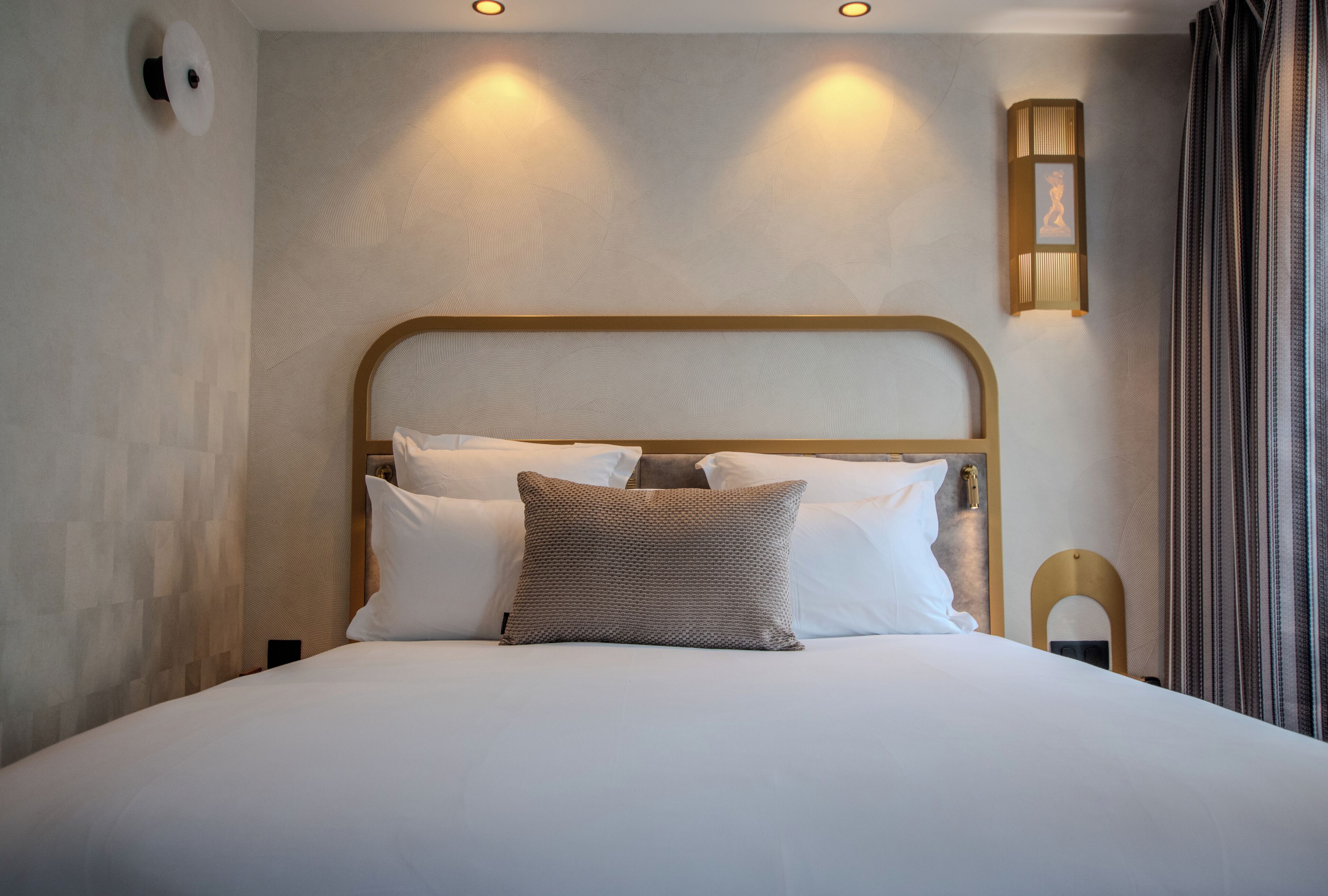 A neatly made bed with a headboard, white bedding, and a patterned pillow.