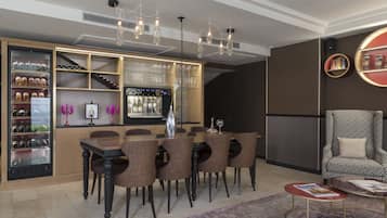 Un comedor moderno con una mesa y sillas de madera, un refrigerador con botellas de vino y una zona de bar con vasos.