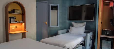 Een hotelkamer met een bed, een bureau met lamp, een televisie en een kledingkast.
