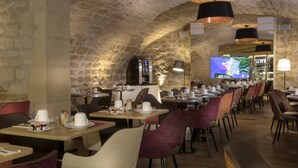 Un restaurante con paredes de piedra, varias mesas y sillas.