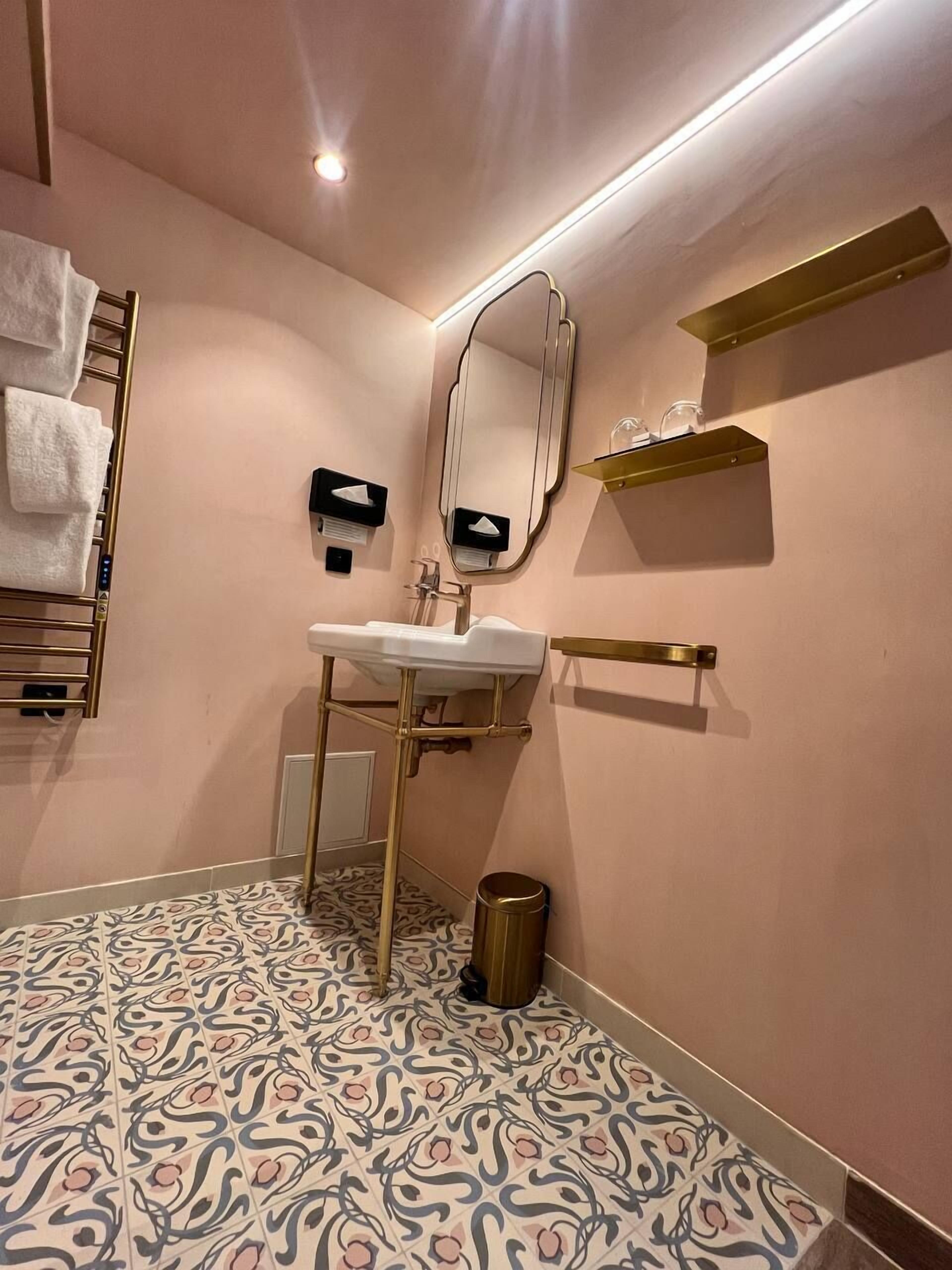 Une salle de bain moderne avec un lavabo, un miroir, un porte-serviettes et un carrelage décoratif.