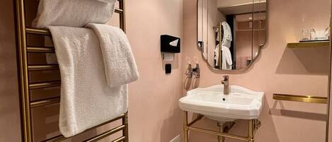 Un baño moderno con un toallero dorado, un lavabo blanco y un suelo estampado.