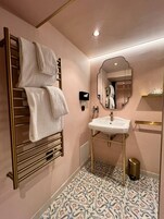A modern bathroom with a gold towel rack, a white sink, and a patterned floor.