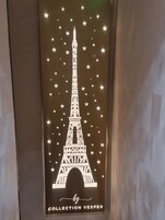 Un panneau décoratif représentant la silhouette de la tour Eiffel, entourée d’étoiles, et portant la mention « Collection Vesper ».