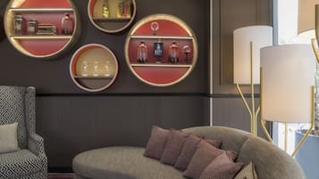 A modern living room with a sofa, patterned armchair, and round wall shelves displaying decorative items.