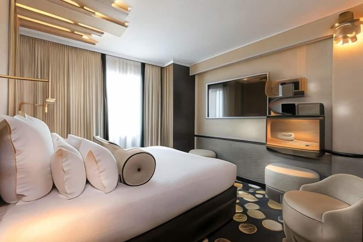 Una habitación de hotel moderna con cama, mesitas de noche, televisor y zona de estar.
