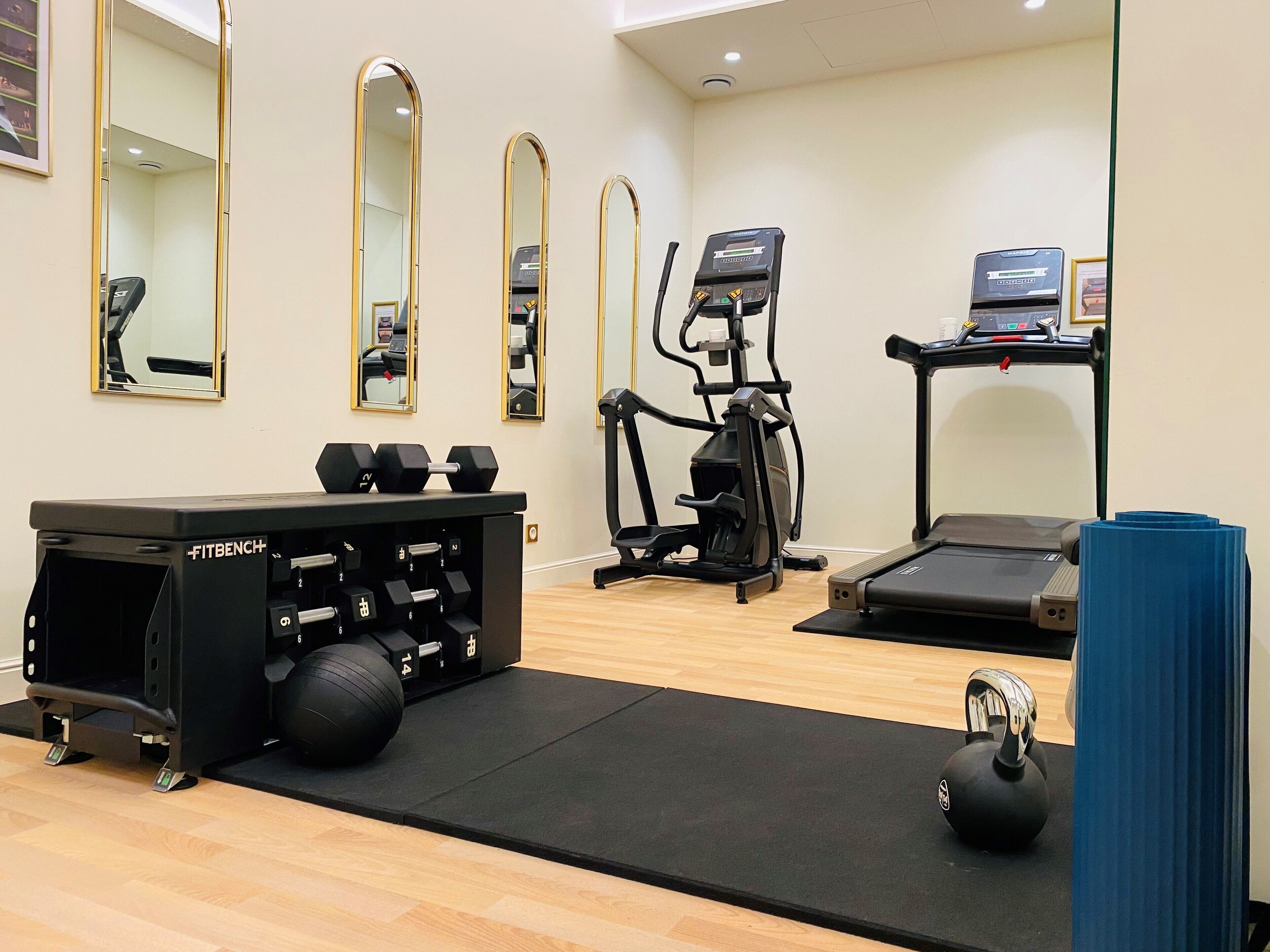 Et træningscenter med løbebånd, crosstrainer, håndvægte, kettlebells og en FITBENCH.