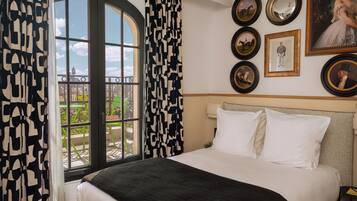 Un cuarto de hotel con una cama grande, vistas a través de una ventana y varias fotografías enmarcadas en la pared.
