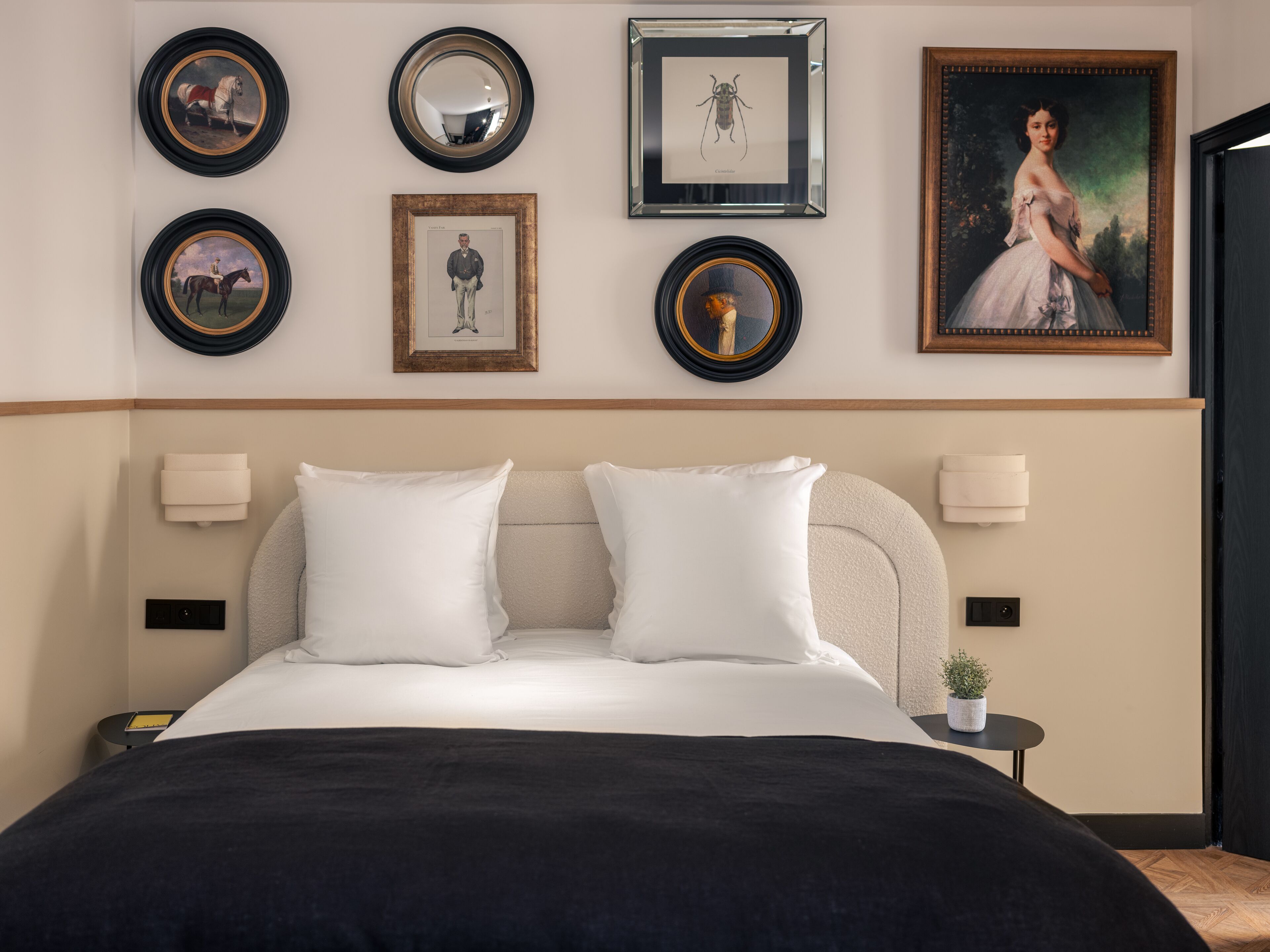 Un dormitorio ordenado con una cama, dos mesitas de noche y una pared decorada con cuadros.
