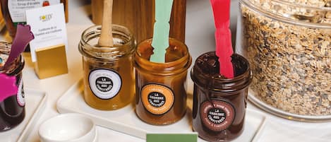 A variety of jars with wooden lids and spoons, some with labels and a card stand.