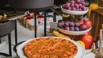 Un buffet de petit-déjeuner avec des croissants, un assortiment de fruits et une pizza.