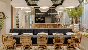 Una sala de estar moderna con sofá, sillas, zona de cocina y ventanas amplias.