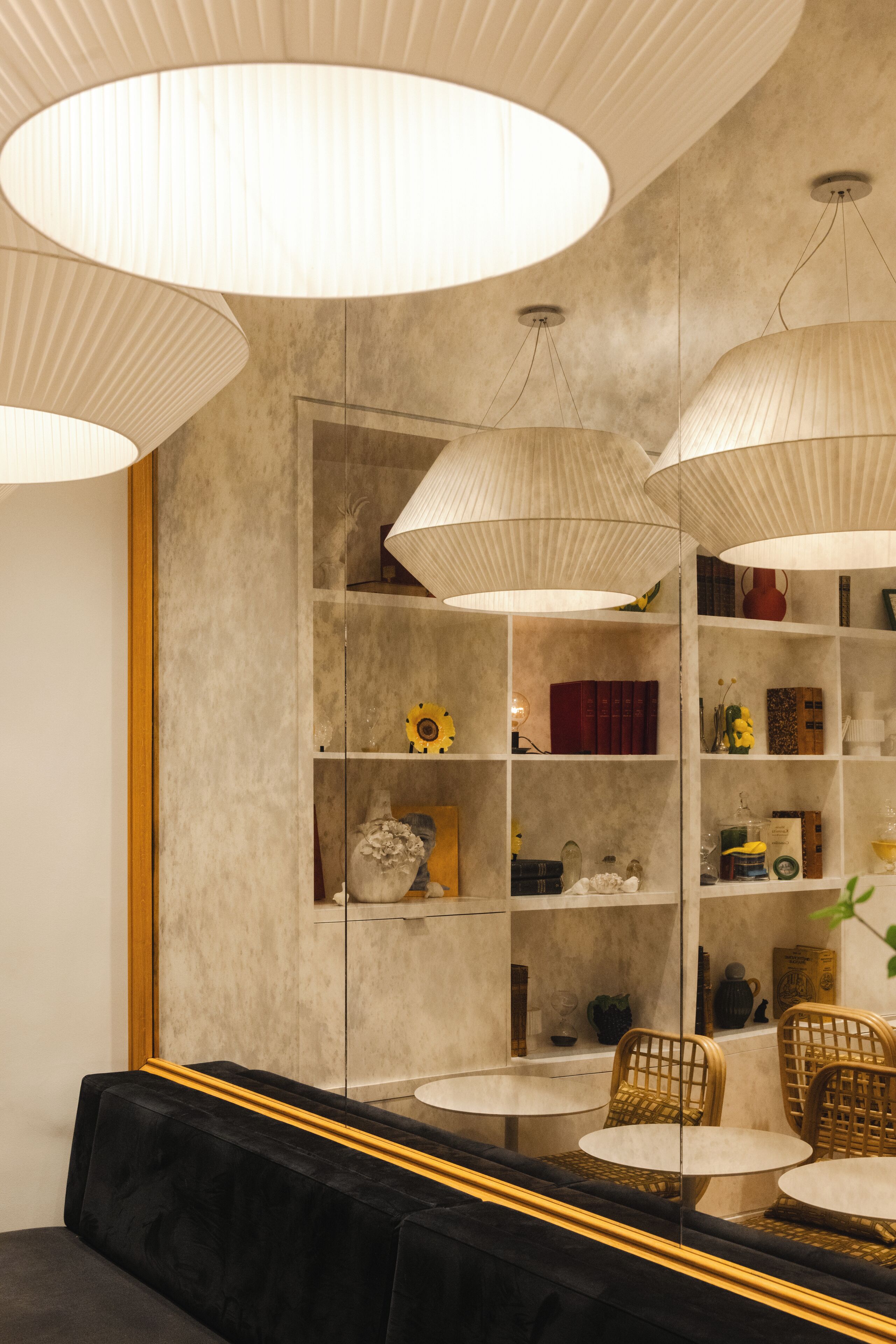 A modern interior with a black sofa, round tables, and a bookshelf with various decorative items.