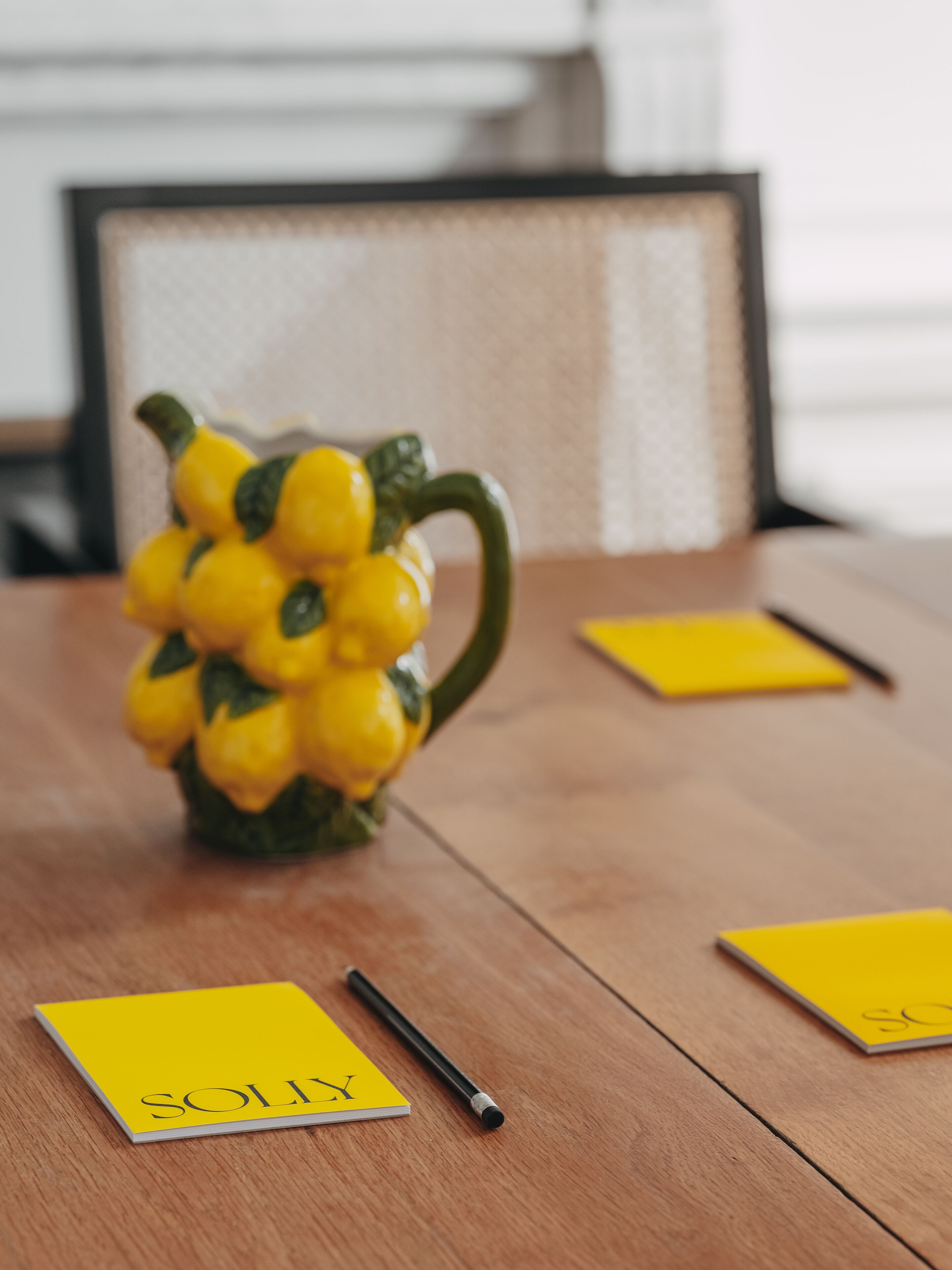 Ett träbord med en gul vas, en svart penna och gula post-it-lappar.