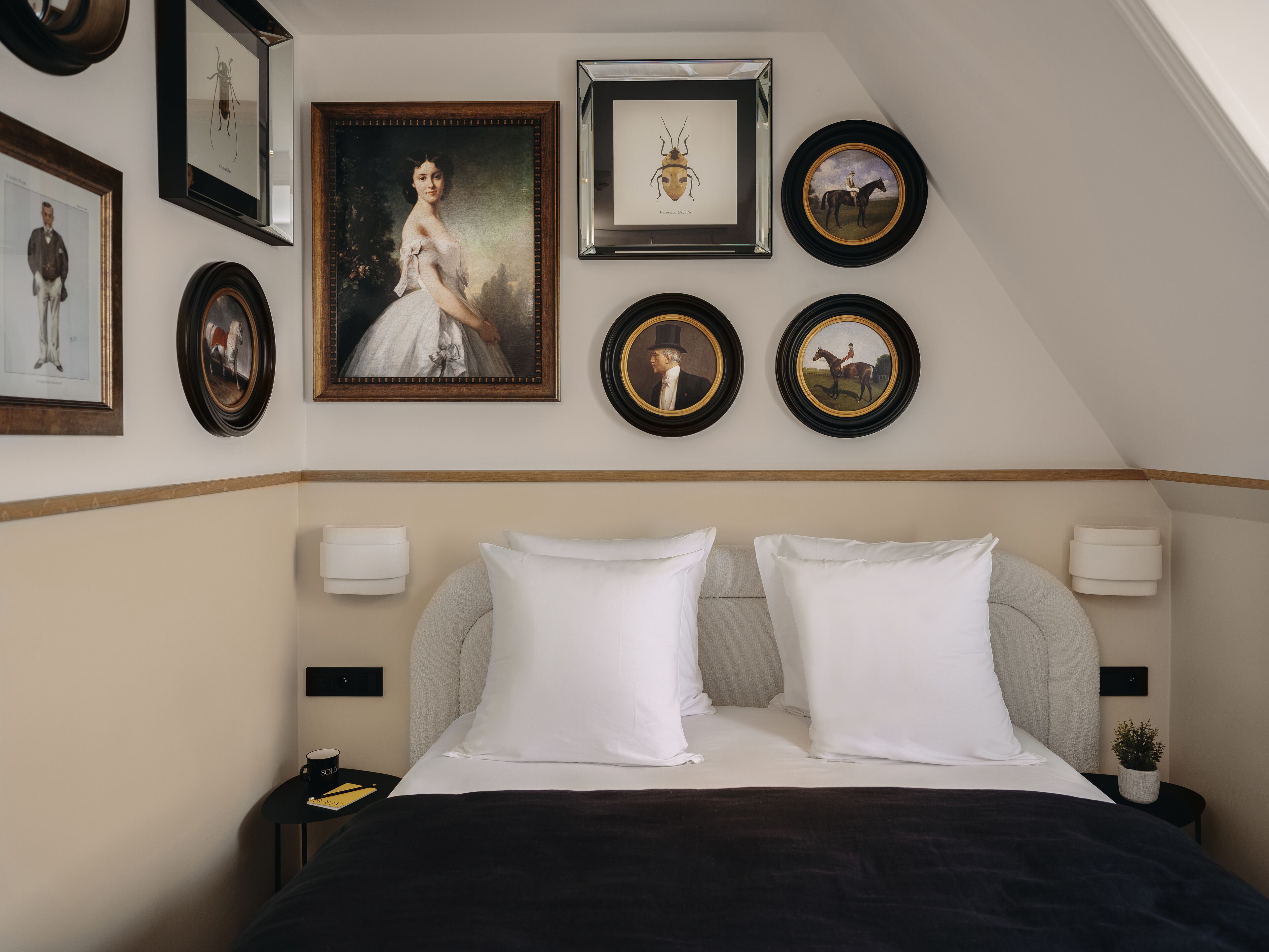 Quarto bem arrumado com uma cama grande, duas mesas de cabeceira e uma parede decorada com quadros e pratos decorativos.