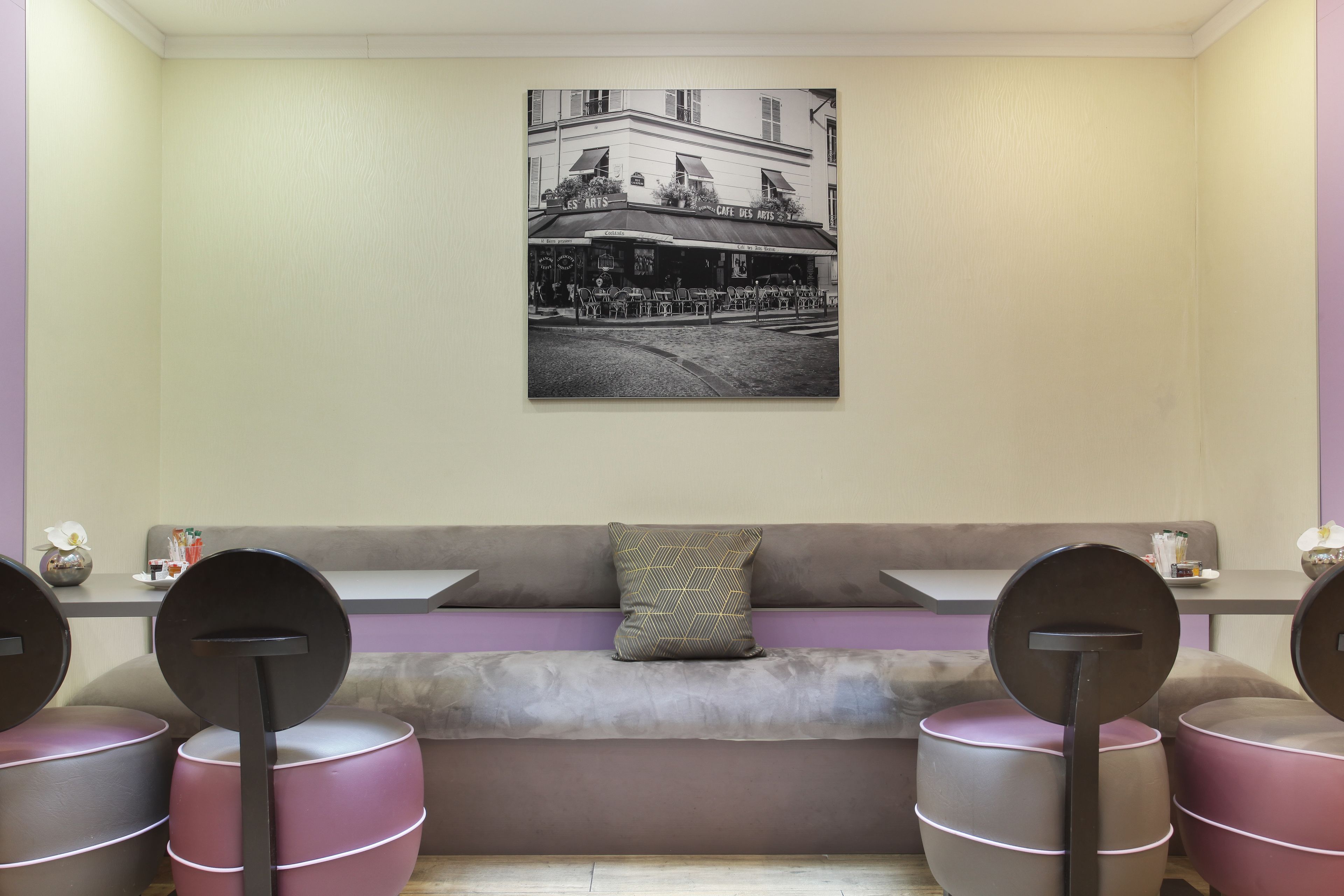 A seating area with a cushioned bench, a wall-mounted picture, and round tables with stools.