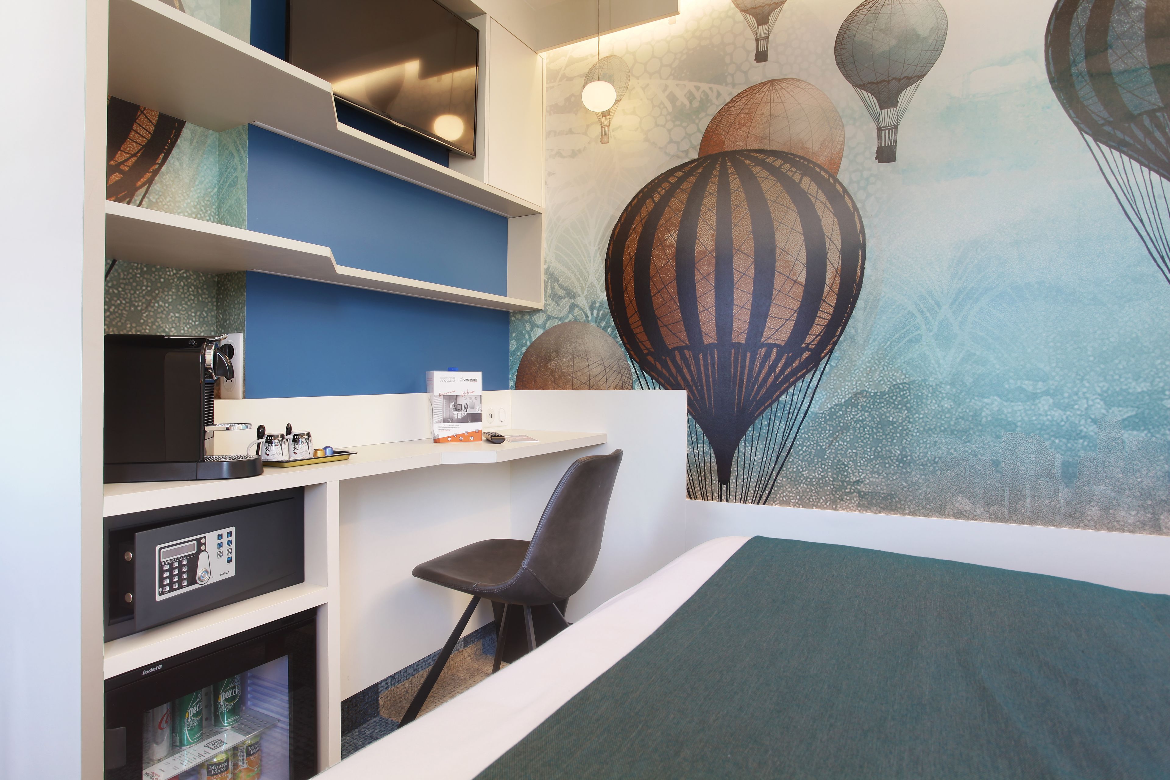 A child's room with a bed, a desk with a computer, a chair, and a wall mural of hot air balloons.