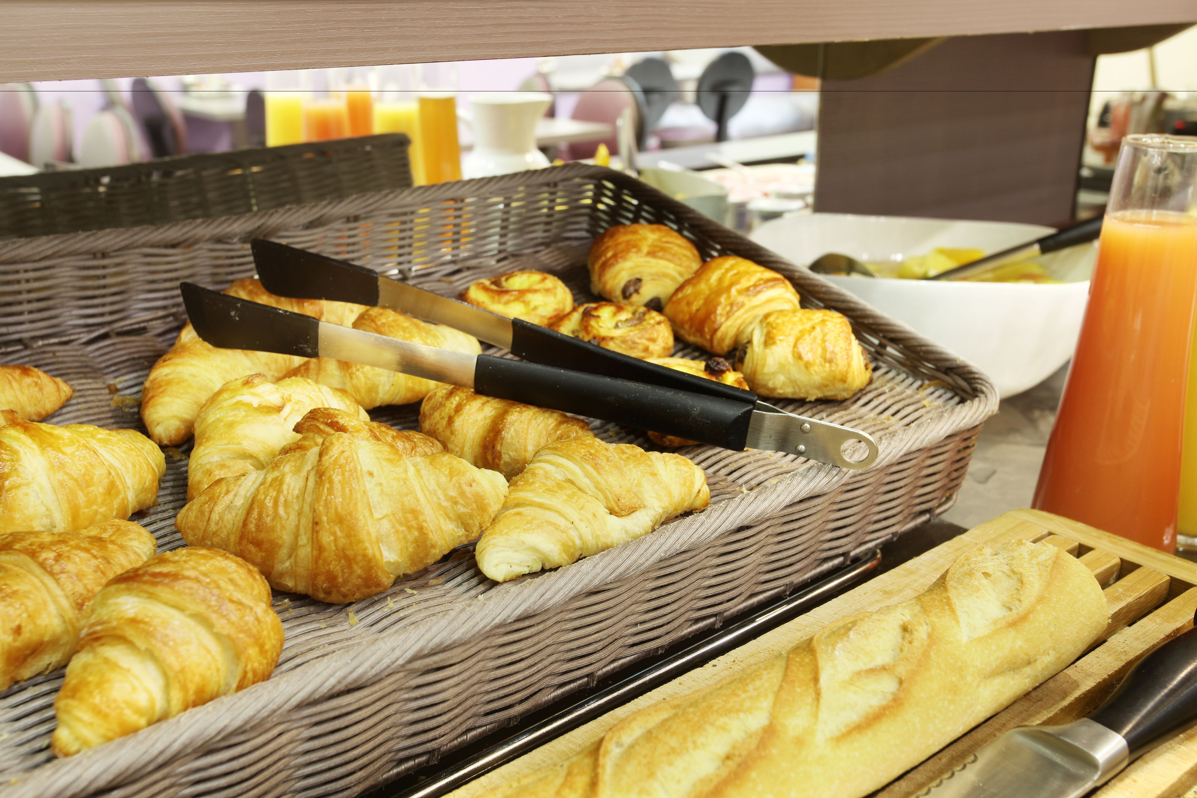 Un bufé de desayuno con cruasanes y un cuchillo sobre una tabla de cortar.