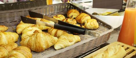 Un bufé de desayuno con cruasanes y un cuchillo sobre una tabla de cortar.