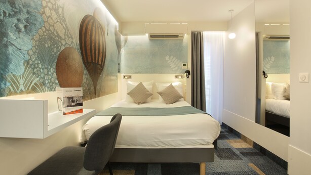 A modern hotel room with a large bed, a bedside table, a chair, and a mirror. - Hotel Apolonia Paris Mouffetard, Sure Hotel Collection by BW (Paris)