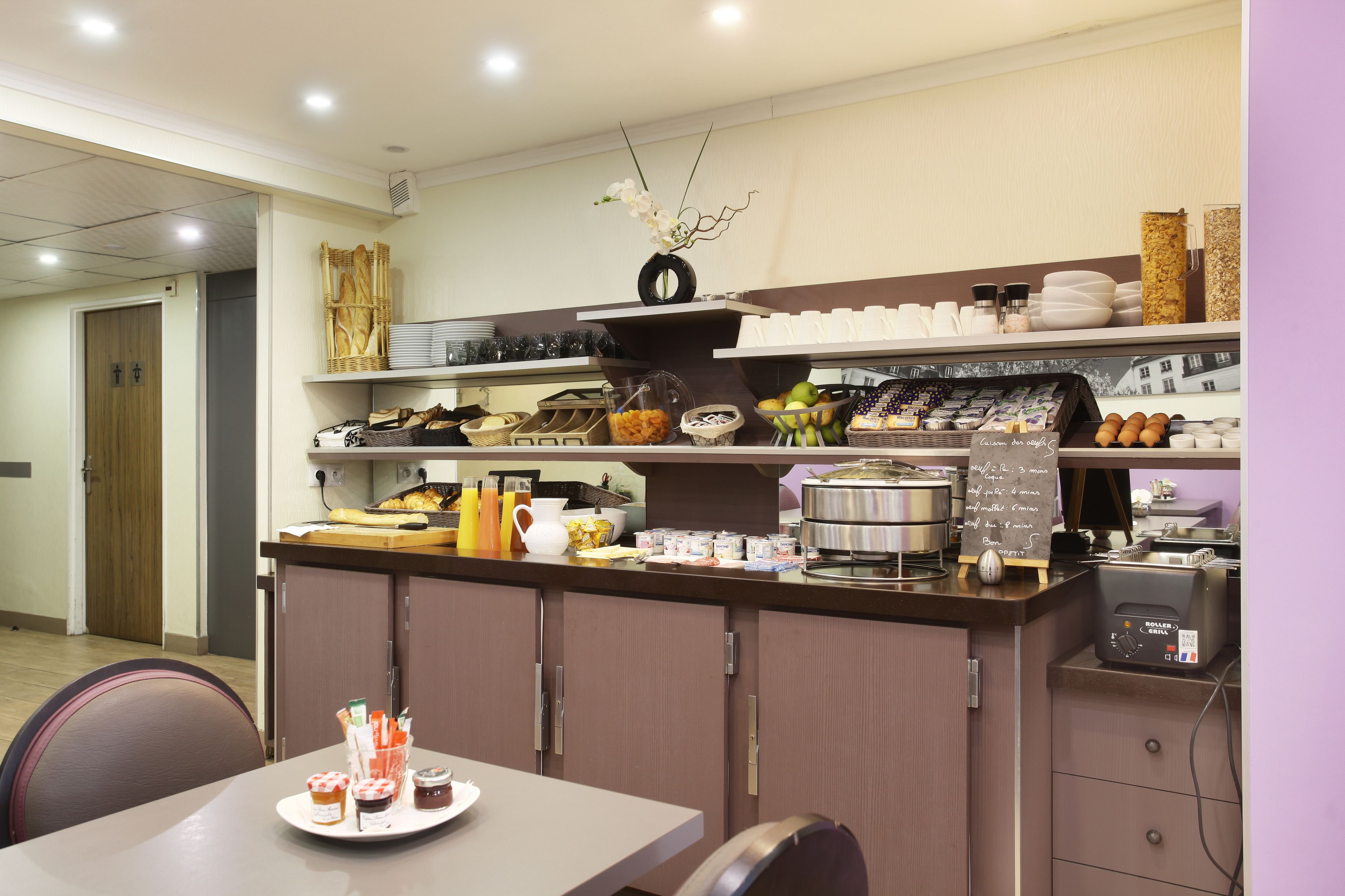 A hotel kitchen with a buffet setup, including a variety of food items and a coffee machine.