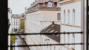 A view through a window of a city street with buildings, a street lamp, and a fence. - Hotel Apolonia Paris Mouffetard, Sure Hotel Collection by BW (Paris)