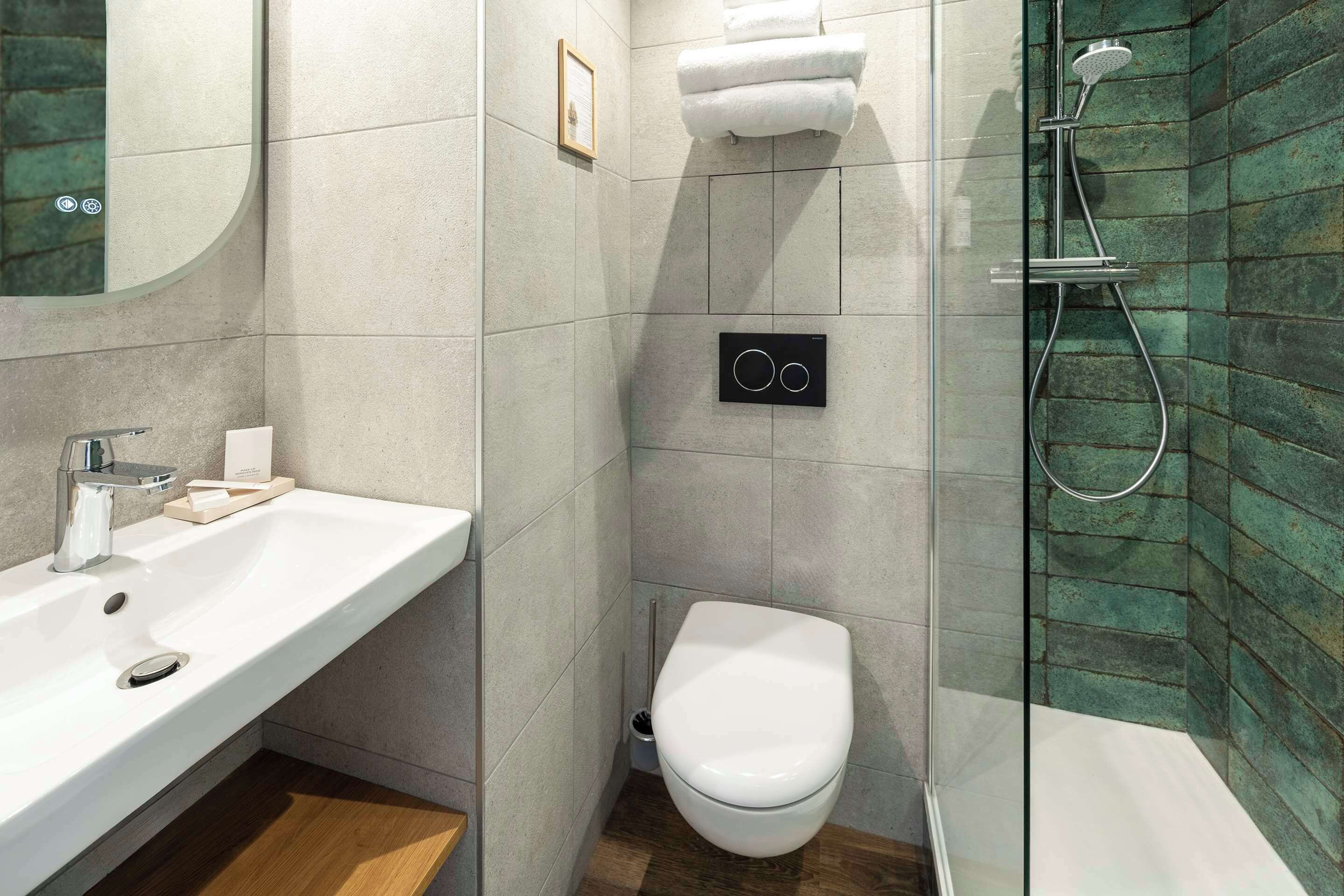 Egy modern fürőszoba, amelyben fehér mosdókagyló, WC és zuhanyzó található.
