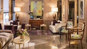 A spacious hotel lobby with a central reception desk, plush seating, and a large abstract painting on the wall. - Balmoral Champs Elysées (Paris)