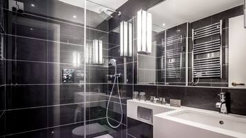 A modern bathroom with a glass-enclosed shower, a large mirror, and a vanity with a sink and towel rack.