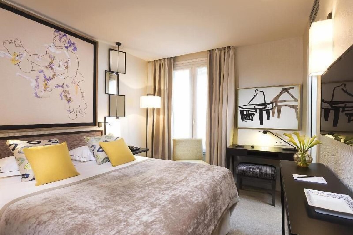 Habitación de hotel con una cama grande, un escritorio, una silla, un mapa en la pared y una ventana con cortinas.