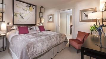 Habitación de hotel con una cama grande, una silla, un escritorio y obras de arte en las paredes.
