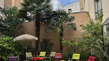 A courtyard with outdoor seating, a palm tree, and a building in the background.