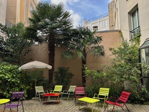 Un patio con mesas al aire libre, una palmera y un edificio en el fondo.