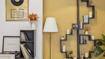 Une pièce avec une bibliothèque, un tourne-disque, une lampe et une étagère murale où sont posés des livres et des bougies.