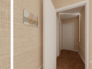 A narrow hallway with patterned walls, a door at the end, and a light fixture above.