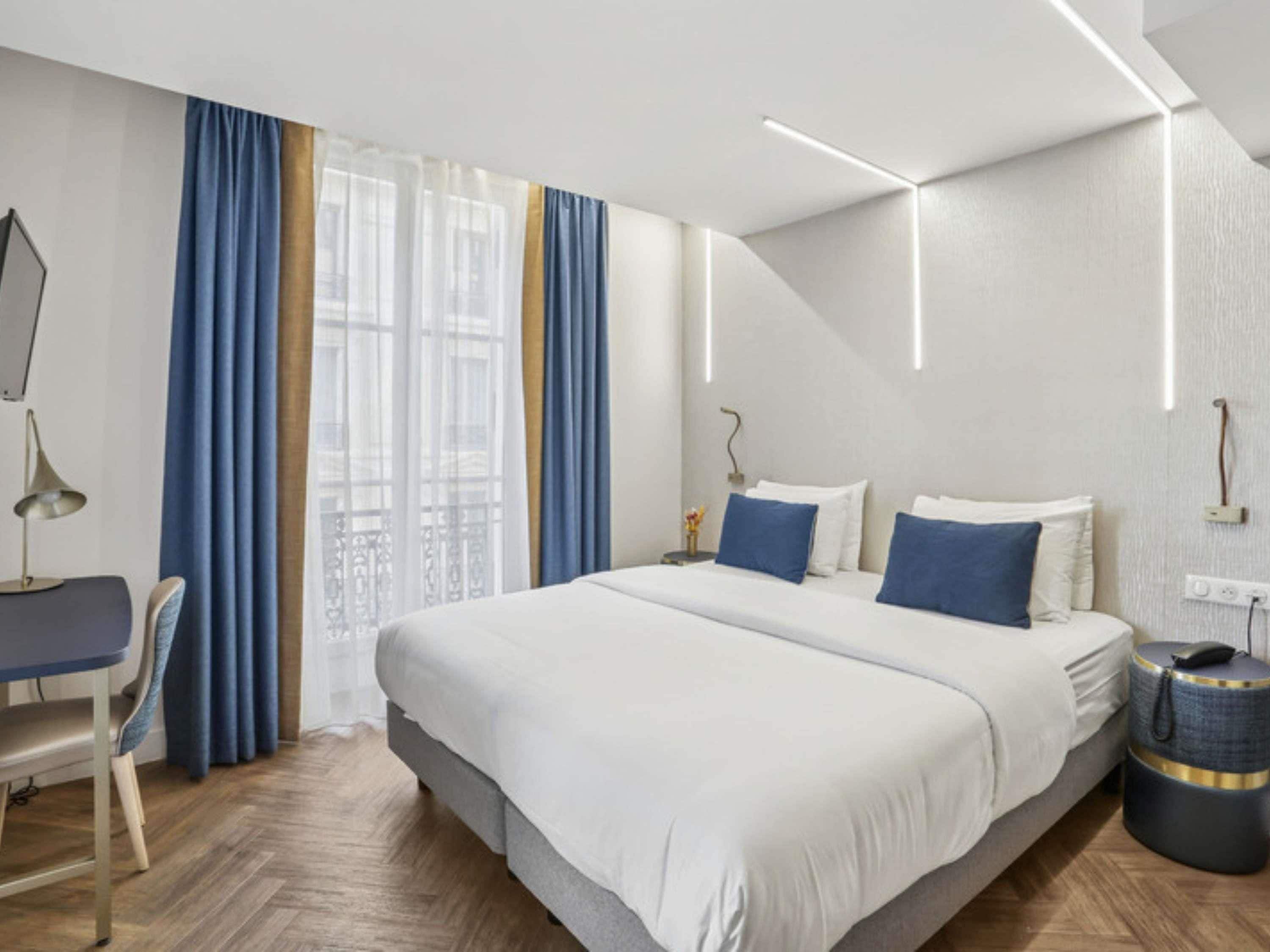Une chambre d’hôtel moderne avec un grand lit, un bureau et une chaise.