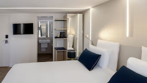 Una habitación de hotel moderna con una cama grande, un televisor de pantalla plana, una mesita de noche y un armario empotrado.