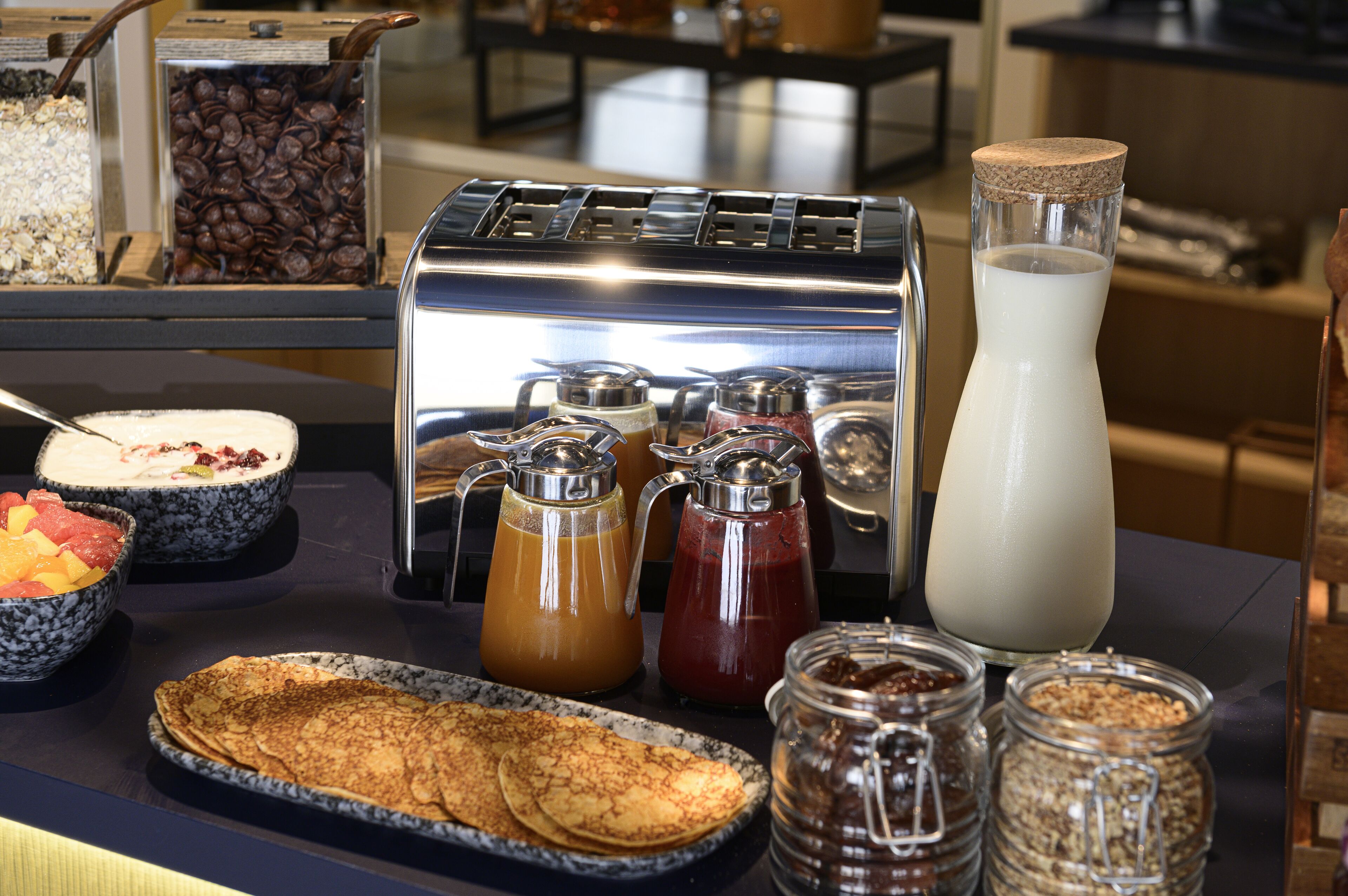 Un buffet de petit-déjeuner proposant une variété d’aliments et de boissons, notamment un grille-pain, des grains de café et un pot à lait.