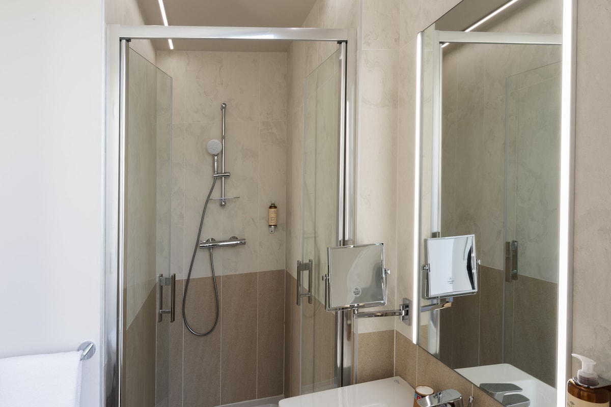 A modern bathroom with a glass-enclosed shower, a built-in sink, and a mirror cabinet.