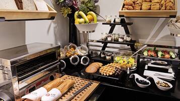 Un buffet con diverse pietanze, tra cui pane, pasticcini, frutta e salse.